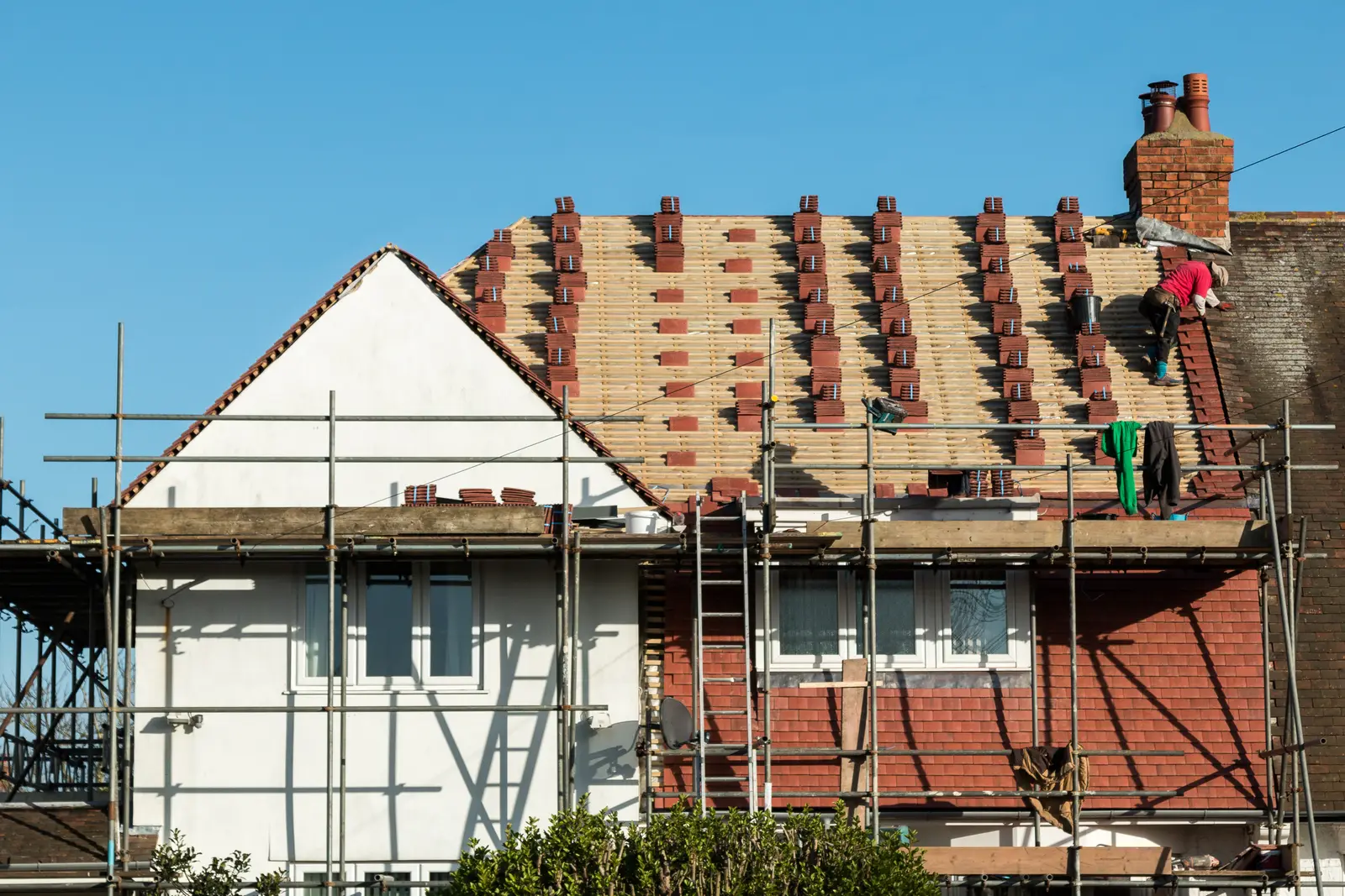 House on scaffolding with tiles loaded out for a re-roof