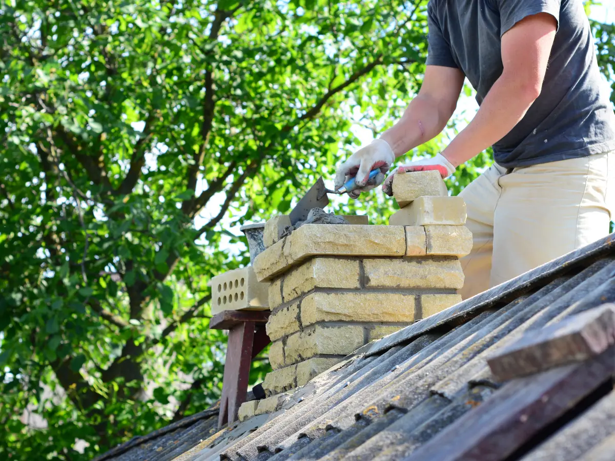 Tradesman rebuilding the top of a chimney stack