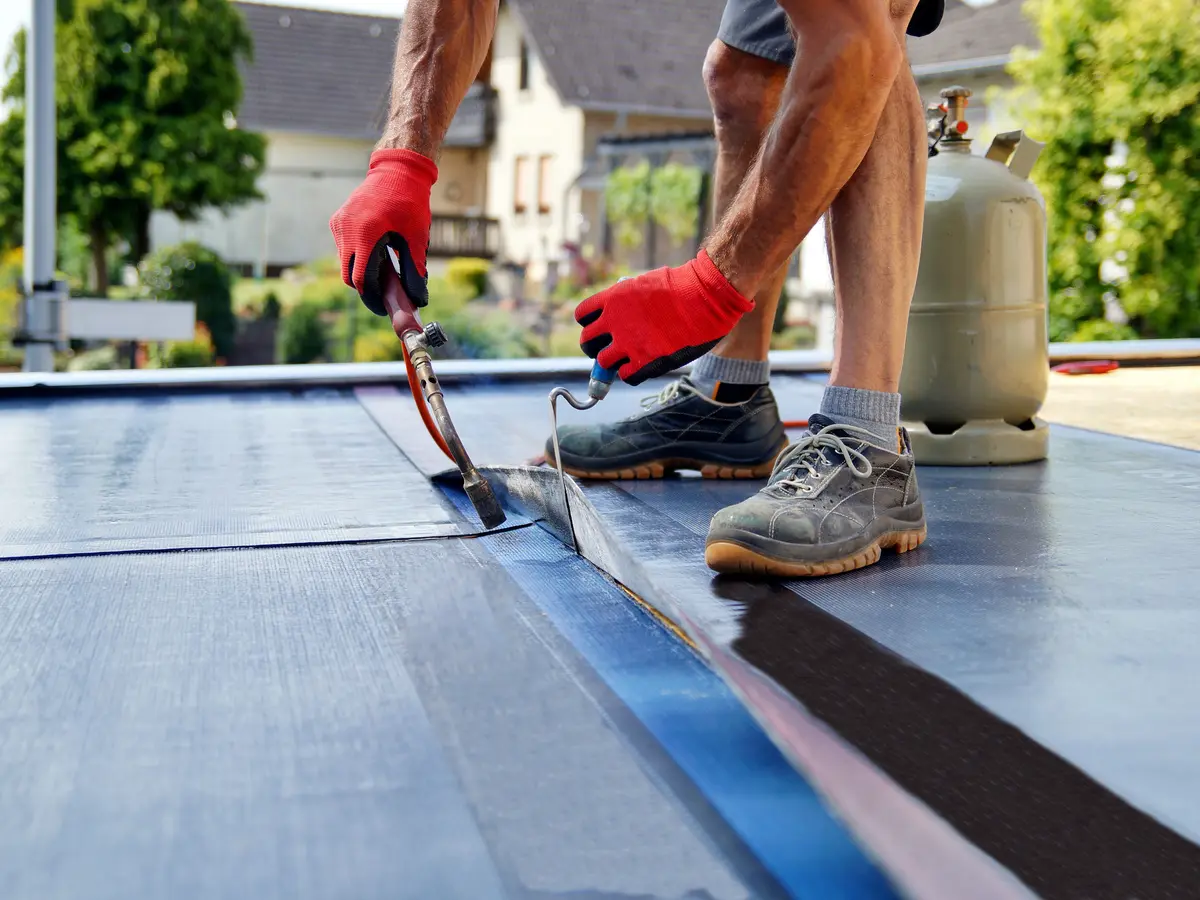 Roofer torching the edge of a new felt flat roof