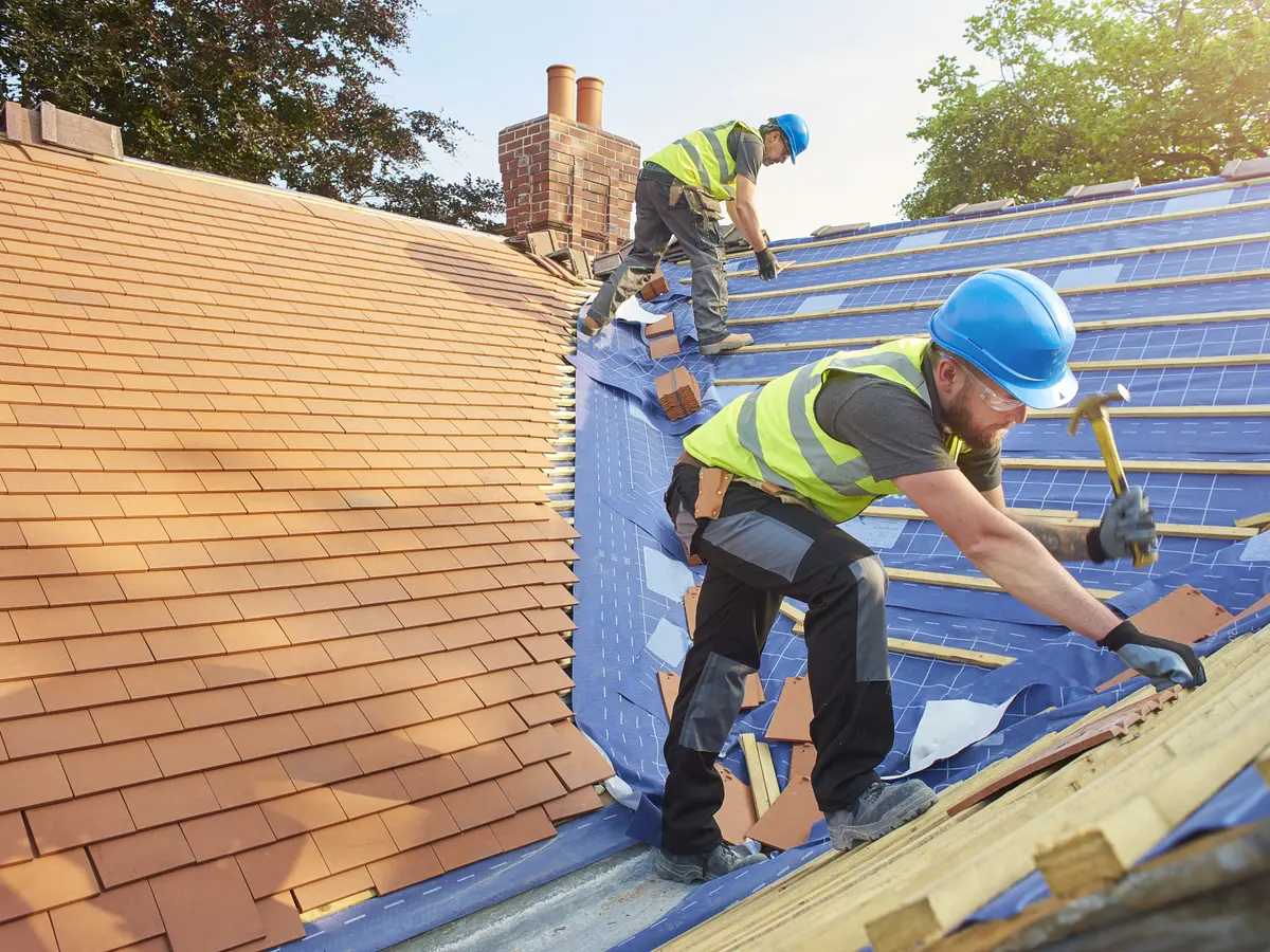 Roofers laying new tiles on a pitched roof