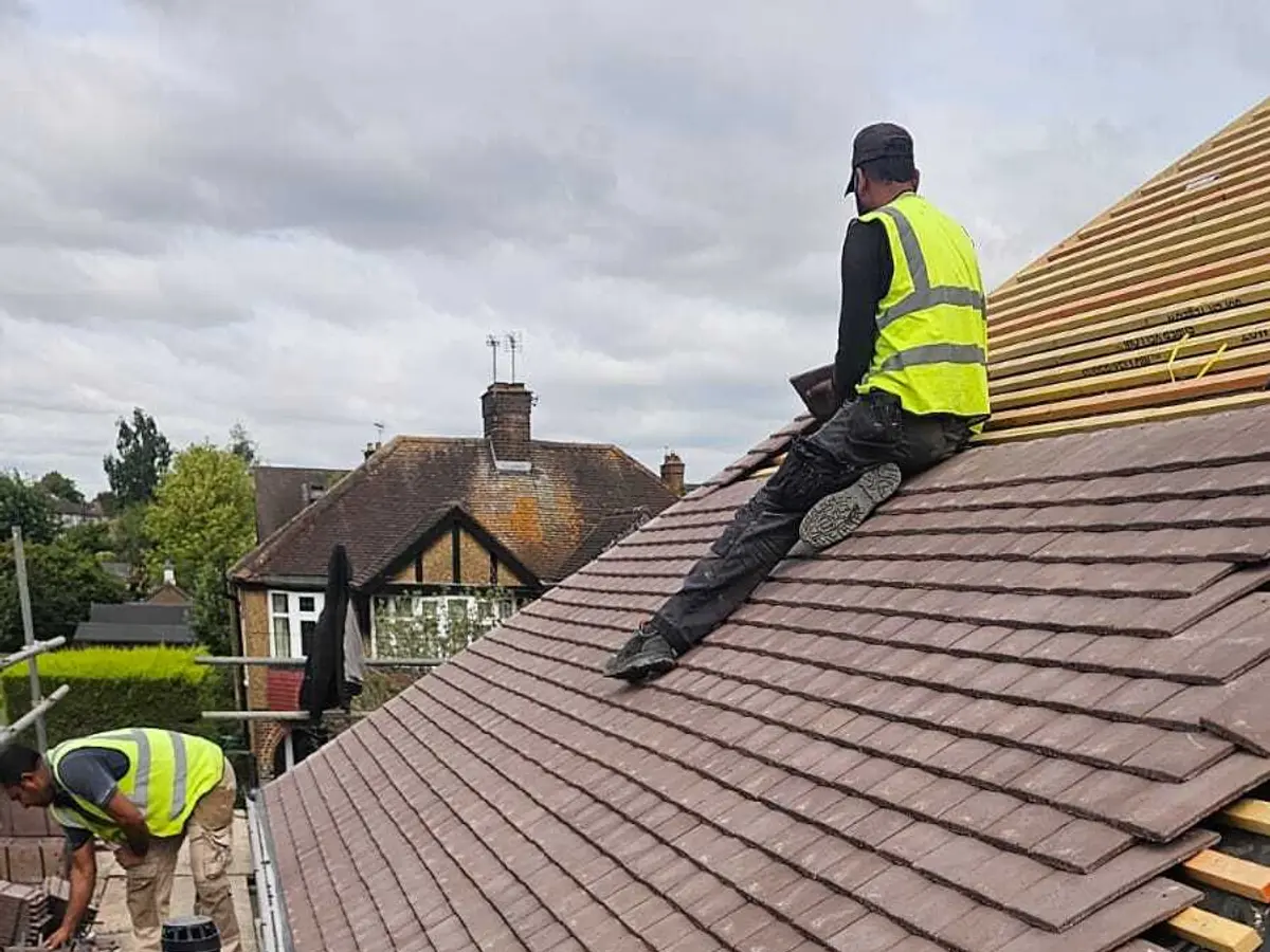 Roofer in hi-vis fitting new plain tiles on a re-roof