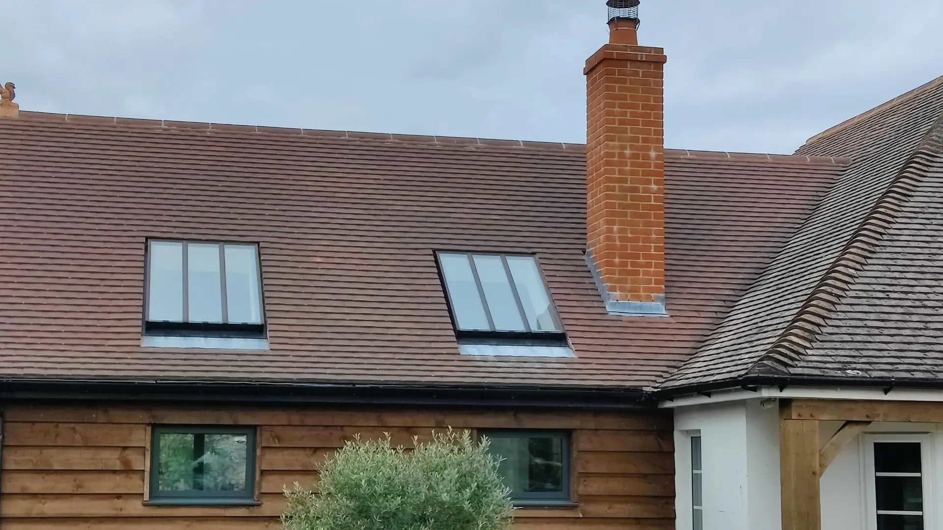 House with a tiled roof, roof windows and a brick chimney