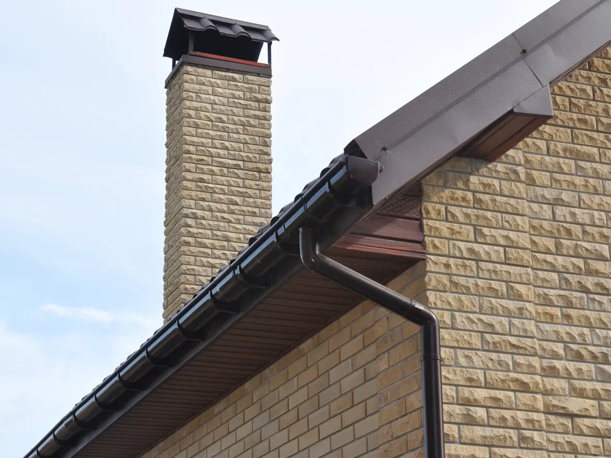 Brown gutter and downpipe on a stone house
