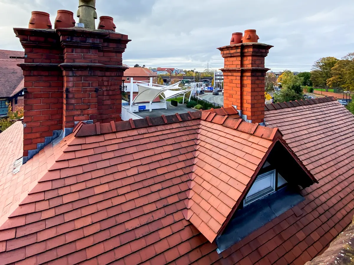 Clay plain tiled roof with a dormer and brick chimneys