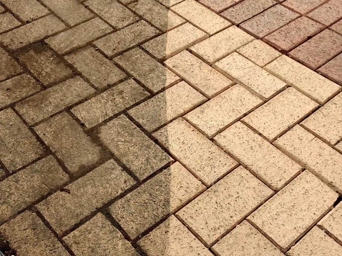 Herringbone block paving with a cleaned strip beside dirty paving
