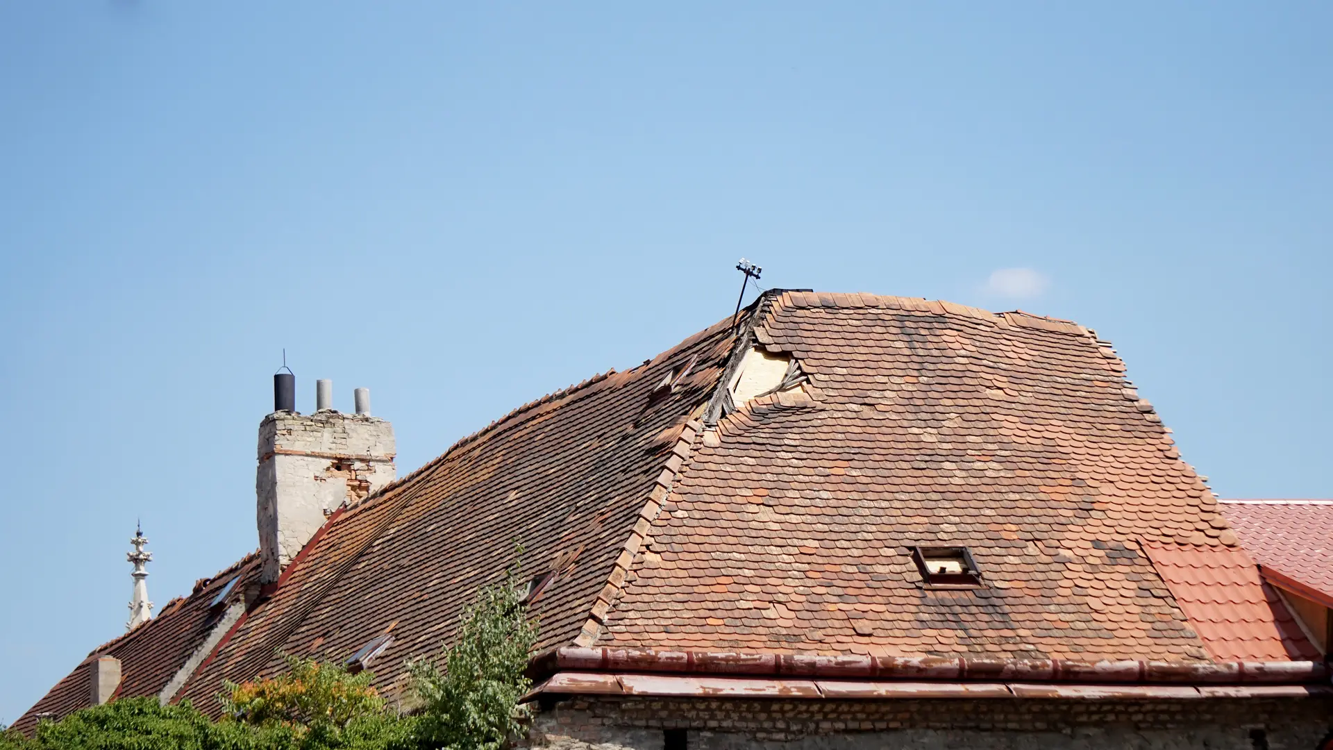 Damaged clay tiled roof with a hole near the ridge