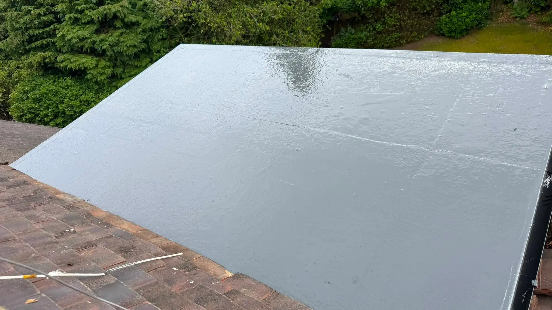 New grey GRP fibreglass flat roof beside a tiled roof