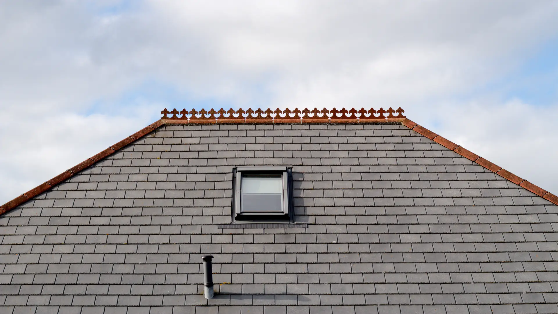 Pitched slate roof with a roof window and clay ridge